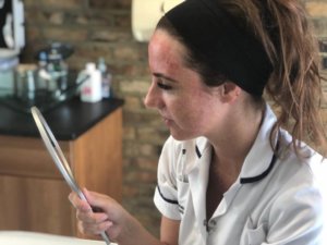 brunette holding a hand mirror and checking out her skin after fusion therapy